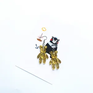 Close-up detail of cute resin glitter bear earrings on display card, stylish accessory.