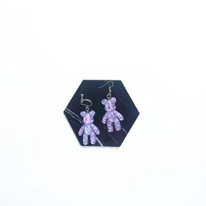 Detail view of purple glitter bear earrings featuring asymmetric clip-on and hook design.