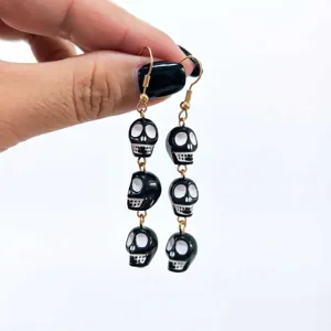 Close-up view of quirky black and white skull dangling earrings, perfect for Halloween party wear.