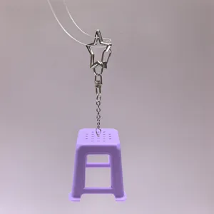 Close-up detail of a creative mini purple stool keychain with a star metal clasp and chain.
