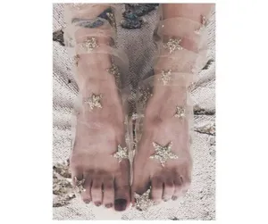 Primo piano di calzini in tulle trasparente con applicazioni di stelle glitterate lucide.