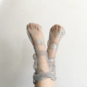 Dettaglio calzini in rete trasparente, tessuto grigio con stelle glitterate argentate, stile alla moda.
