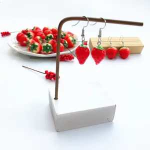Detailed view of handmade cute red strawberry resin drop earrings, sweet summer style jewelry.
