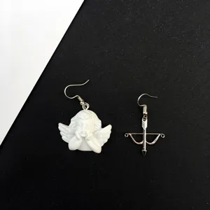 Detalle de pendientes de flecha de ángel asimétrico, joyería estilo cupido barroco retro.