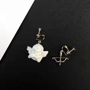 Primer plano de los detalles de los pendientes de clip asimétricos de ángel y arco.
