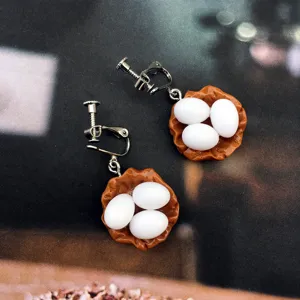 Gros plan de clips d'oreilles nid d'œufs de fantaisie faits main, bijoux originaux en résine.