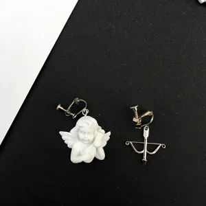 Detalle de pendientes de clip asimétricos ángel y arco de estilo barroco vintage