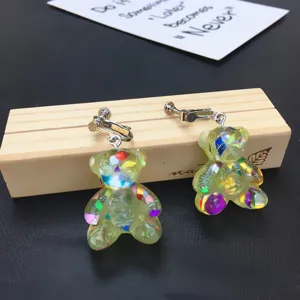 Close-up detail of cute handmade resin glitter bear clip-on earrings with sparkly colorful flakes.