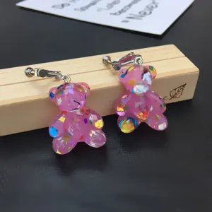Cute pink resin bear earrings with colorful foil flakes, clip-on style jewelry detail shot.