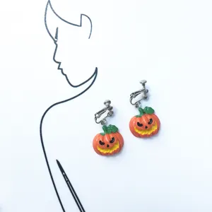 Detailed shot of cute Halloween pumpkin clip-on earrings, funny smiling design, alloy metal.