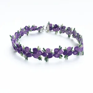 Vue rapprochée d'un collier choker en dentelle brodée de fleurs violettes et feuilles.