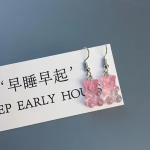 Gros plan de boucles d'oreilles ours en gelée pailletées roses, jolies paires en résine.