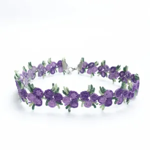 Gros plan sur les détails du collier choker en dentelle avec des fleurs violettes.