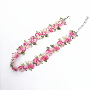 Vue détaillée du collier ras de cou en dentelle brodée de fleurs roses avec fermoir.