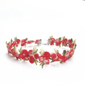 Gros plan sur le collier choker brodé de fleurs rouges et vertes montrant de fins détails.