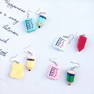 Close up of cute handmade miniature pencil and test paper asymmetric earrings detailing.