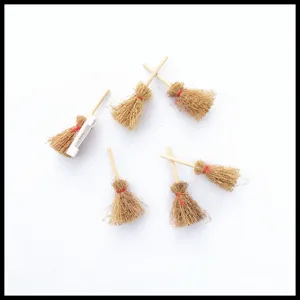 Vista detallada de broche escoba de bruja en miniatura, diseño de madera y paja con imperdible.