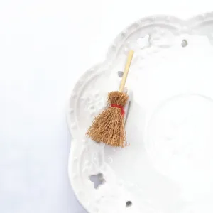 Primer plano detalle de un broche en miniatura de escoba de bruja, accesorio gracioso.