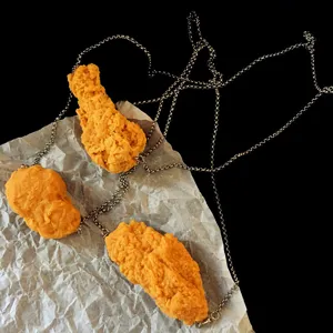 Detailaufnahme der kreativen Hähnchen-Nugget-Halskette mit lustigem Anhänger und feinen Metallketten.