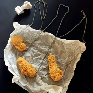 Nahaufnahme einer kreativen künstlichen Hähnchen-Nugget-Halskette mit filigraner Metallkette.