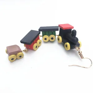 Gros plan des boucles d'oreilles train en bois coloré montrant les wagons et le crochet doré.