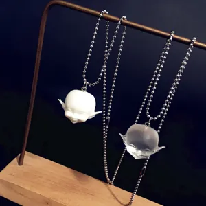 Gros plan détail du collier pendentif tête d'elfe souriante en résine avec chaîne.