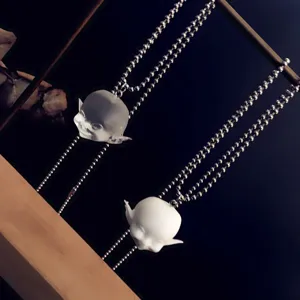Vue rapprochée du collier pendentif tête d'elfe souriant en résine avec chaîne argentée.