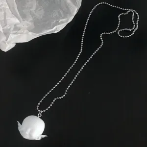 Detail de collier tete elfe souriante en resine mate, bijou de niche poupee mignonne.