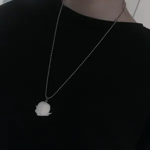 Gros plan du collier pendentif poupée en résine blanche sur chaîne argent, bijou de niche.