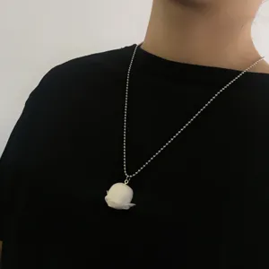 Gros plan d'un joli collier avec pendentif tête d'elfe en résine mate blanche porté.