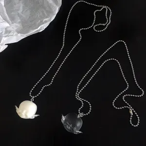 Vue détaillée des colliers pendentifs tête de poupée elfe en résine, mat et transparent.
