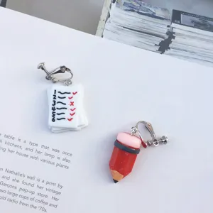 Quirky asymmetrical clip-on earrings featuring cute test paper and red pencil design for students.