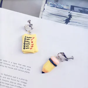 Detailed view of creative handmade student asymmetrical earrings featuring funny pencil and paper design.