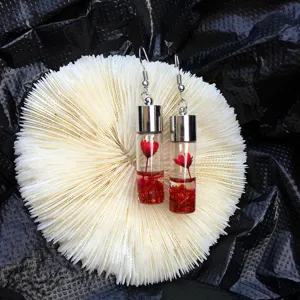 Detailed view of clear glass bottle earrings featuring a charming red flower and sparkling glitter.