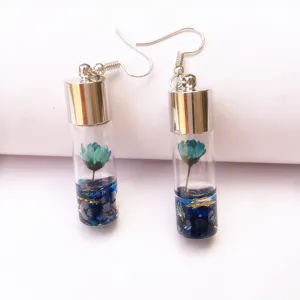 Close-up detail of blue dried flower glass vial earrings with silver plated hooks.