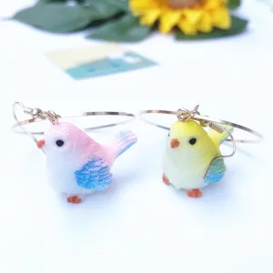 Vue de détail de boucles d'oreilles oiseau potelé avec charm animal en résine et crochet en métal.