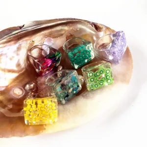 Primer plano detallado de anillos gruesos de resina acrílica colorida con cuentas incrustadas.