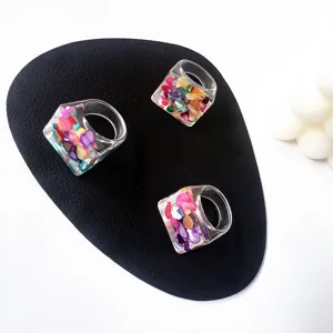 Detalle en primer plano de anillos de acrílico transparente con piedras de colores incrustadas.