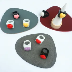 Vue détaillée de bagues cœur en résine colorée sur coussinets, bijoux style bonbon tendance.