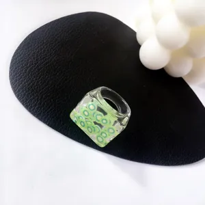 Primer plano de un anillo de resina transparente con rodajas de kiwi verde incrustadas.