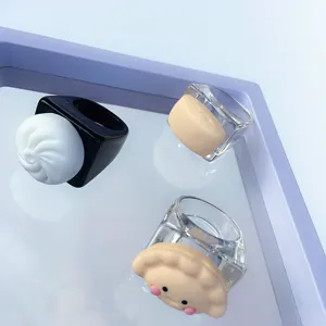 Close-up detail of cute resin acrylic food rings with fun cartoon bun and dumpling designs.