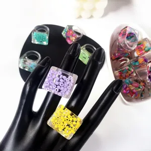 Primer plano detallado de anillos gruesos de resina acrílica con cuentas de colores incrustadas.