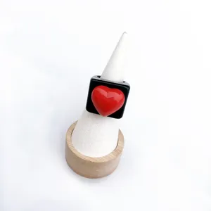 Vue détaillée de la jolie bague carrée en résine noire avec un design de cœur rouge.