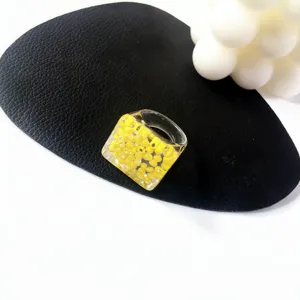 Primer plano de anillo de acrílico de resina grueso con cuentas amarillas incrustadas, joya retro.