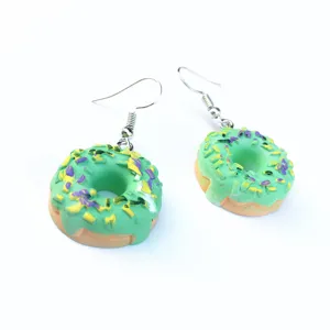Nahaufnahme von handgefertigten grünen Donut-Ohrringen mit bunten Streuern und Metallhaken.