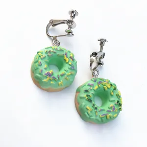 Nahaufnahme Detail süßer grüner Donut Clip-Ohrringe mit bunten Streuseln und Metallschraube.