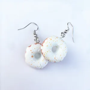 Nahaufnahme der handgemachten Donut-Ohrringe mit süßem weißem Zuckerguss und bunten Streuseln.
