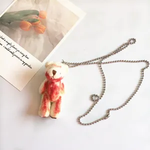 Close-up detail van de griezelige schattige bebloede knuffelbeer hanger met metalen kogelketting.
