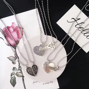 Detail shot of matching heart and key pendant necklaces with engraved love and friendship text.