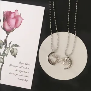 Detailed view of couple matching coin necklaces with intricate cut-out designs on ball chains.
